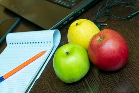 Write ideas into a notebook with a pen, laptop, headphones and apples for hea Stock Photos
