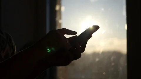 Write something on the phone screen on a sunset background with beautiful Stock Footage 72178166