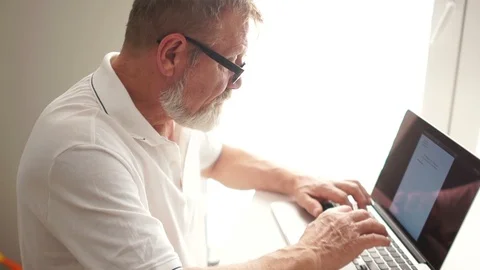 Writer or scientist at work. A senior citizen writes a letter using a computer Video stock 120792842