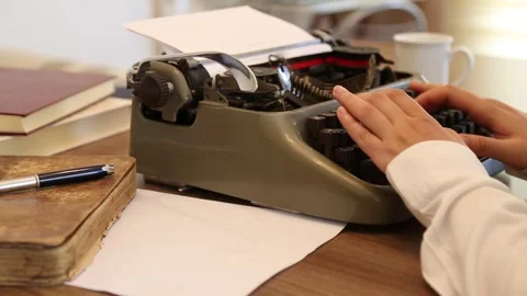 Writer typing on an old typewriter on the desk with a cup of coffee and books. Stock Footage 338027923