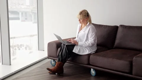 Writer working on laptop by window in modern apartment Video stock 308436399