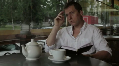 A writer writes poetry and write them in notebook sitting in a summer cafe Stock Footage 68175133