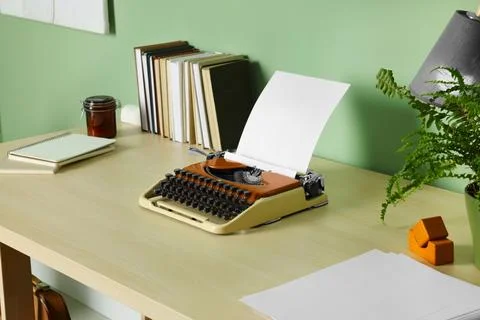 Writer's workplace with typewriter on wooden desk near pale green wall in roo Stock Photos
