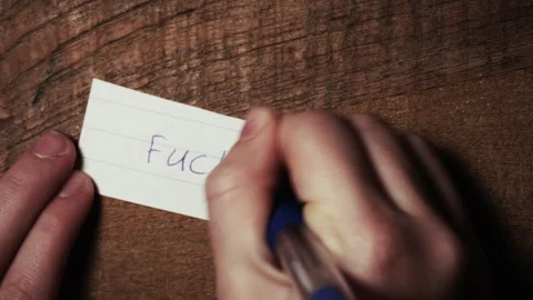 Writing with ballpoint pen on small note "fuck you" Stock Footage 301999198