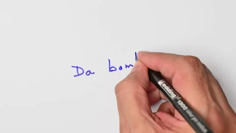 Writing with a blue marker the sentence: Da bomb Stock Footage 221782394