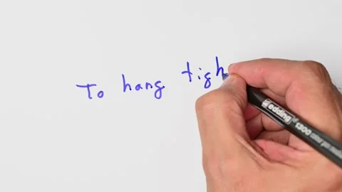 Writing with a blue marker the sentence: To hang tight Stock Footage 221782363