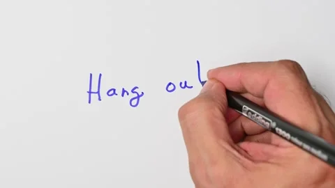 Writing with a blue marker the sentence: Hang out Stock Footage 221782740