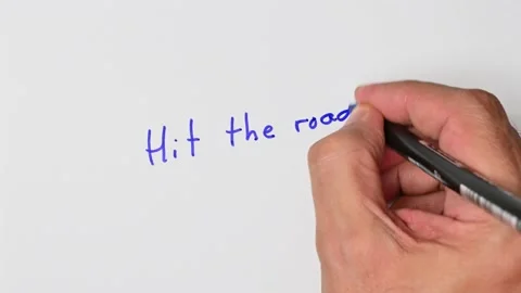 Writing with a blue marker the sentence: Hit the road Stock Footage 221781986
