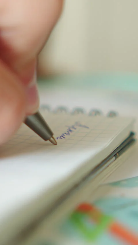 Writing in a book. Close up shot of a hand holding a pen and writing in a b.. Video stock 337153143
