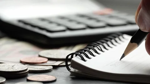 Writing Financial Calculations in Notebook With Coins and Calculator Video stock 346730553