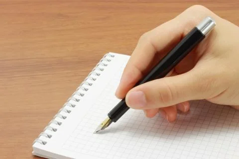 Writing hand in an open notepad Stock Photos