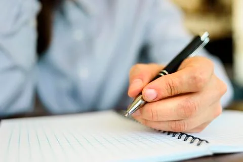 Writing by left hand with pen on notebook Stock Photos