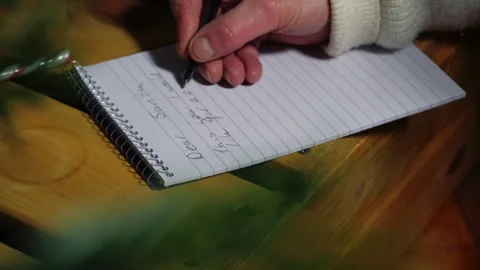 Writing a letter to Santa on notepad view through Christmas tree Stock Footage 326359319