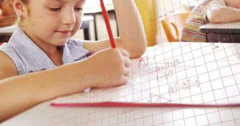 Writing math equations boy sitting at school desk on graph paper in classroom, Stock Photos