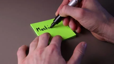 Writing "Meeting at 11 a.m." on a post-it note Stock Footage 147137889