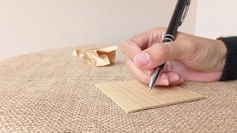 Writing a note on a brown paper and brown table Stock Footage 151027410