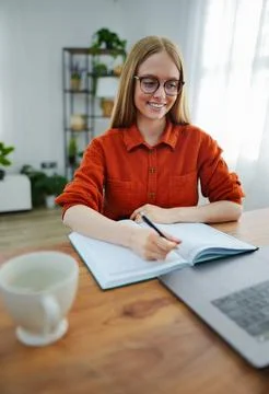 Writing in a notebook while enjoying a cozy home workspace Stock Photos