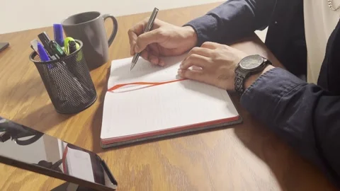 Writing in a notebook at a wooden desk, close-up view Stock Footage 345150809