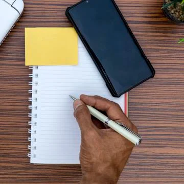 Writing on a notepad while working from home. A lap top, a mobile, calculator Stock Photos