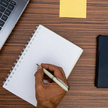 Writing on a notepad while working from home. A lap top, a mobile, calculator Stock Photos