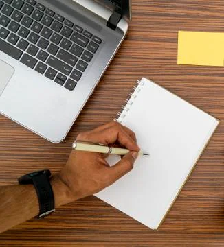 Writing on a notepad while working from home. A lap top, a mobile, calculator Stock Photos