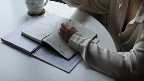 Writing notes at a cozy desk in a bright cafe setting Stock Footage 301700487