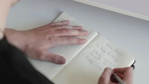 Writing Notes in a Notebook – Over the Shoulder View Stock Footage 302580006