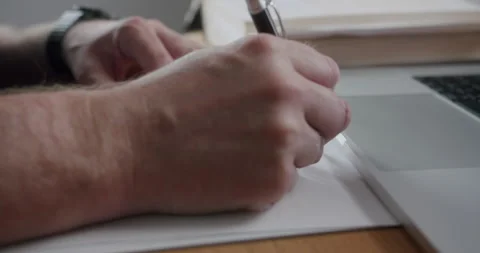 Writing notes on paper while using a laptop in a workspace during the day Stock Footage 327502929