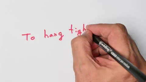 Writing with a red marker the sentence: To hang tight Stock Footage 221781953