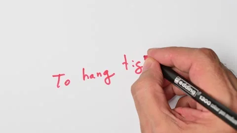 Writing with a red marker the sentence: To hang tight Stock Footage 221782431