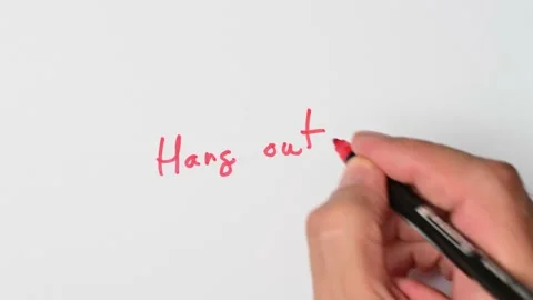 Writing with a red marker the sentence: Hang out Stock Footage 221782777