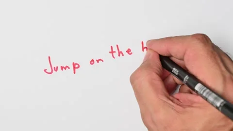 Writing with a red marker the sentence: Jump on the bandwagon Stock Footage 221783490