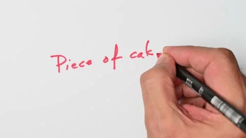 Writing with a red marker the sentence: Piece of cake Stock Footage 221782854