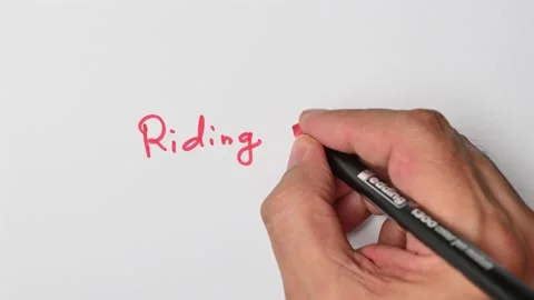 Writing with a red marker the sentence: Riding shotgun Stock Footage 221783870
