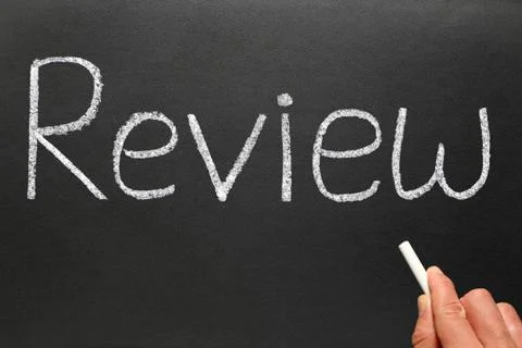 Writing review with white chalk on a blackboard. Stock Photos