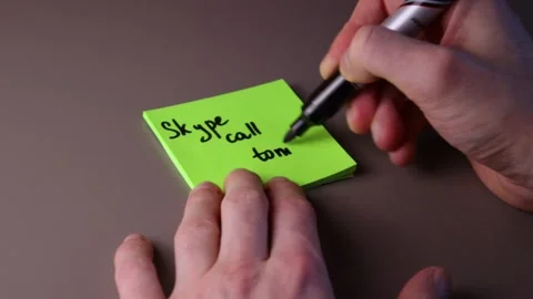 Writing "Skype call tonight" on a post-it note Stock Footage 147138306