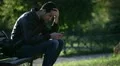 Writing sms/email on smartphone in a park (worried guy on a bench) HD Footage