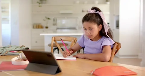 Writing student studying at home table on tablet ping tapping tablet while Stock Footage 336784711