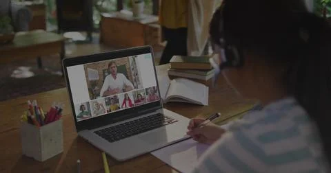 Writing student wearing headset in virtual class at table, with laptop notebook Stock Photos