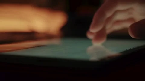 Writing on a Tablet Screen in a Dimly Lit Room with Fingers Moving Stockbeeldmateriaal 331170403