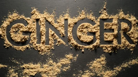 Writing word "Ginger" from  dry ginger powder on black background. Stop motion. Видео 144416130