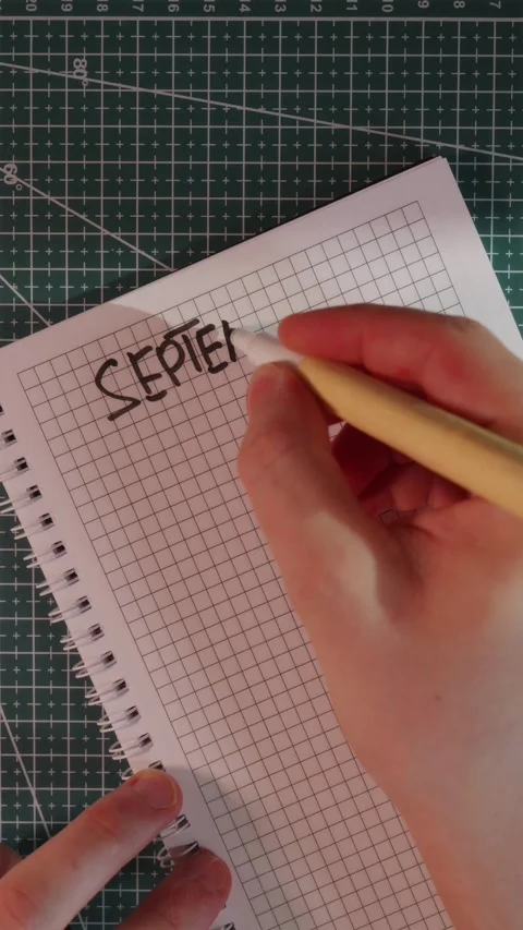 Writing word September in notebook on green cutting mat Stock Footage 341246025