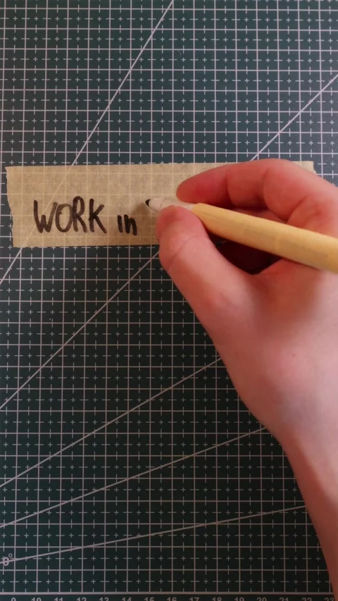 Writing WORK IN PROGRESS on tape on empty green mat. Stock Footage 337816396
