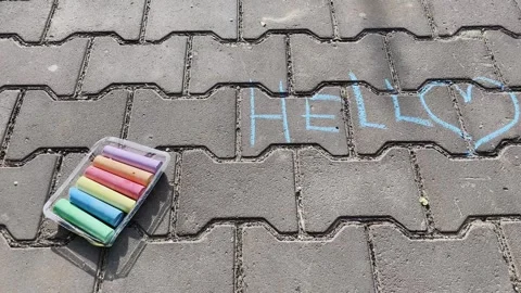 Written Hello in colored crayons on the asphalt. Colorful chalks on a street, a Stock Footage 240743205