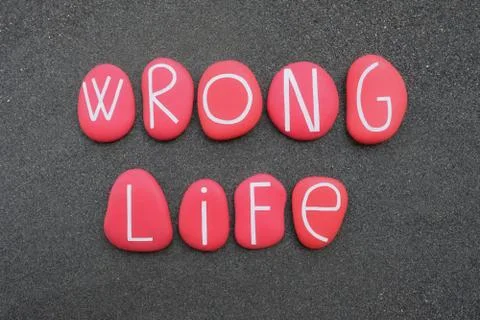 Wrong life text composed with red colored stone letters over volcanic sand Stock Photos
