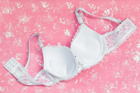 Wrong side of white lace bra on a pastel pink background with white spots. Stock Photos