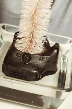 Wrong way cleaning sensor of digital camera by service man in water Stock Photos