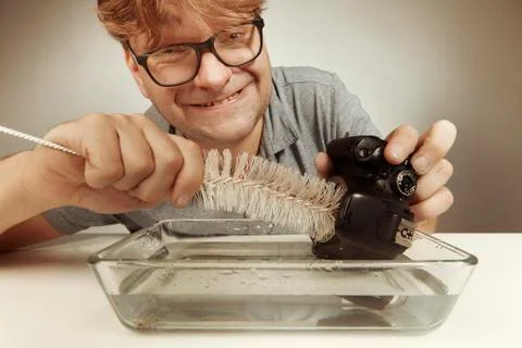 Wrong way cleaning sensor of digital camera by service man in water Stock Photos