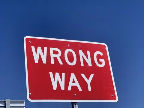 Wrong way direction sign post Stock Photos