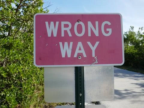 Wrong way sign close-up on road on natural park access road Stock Photos